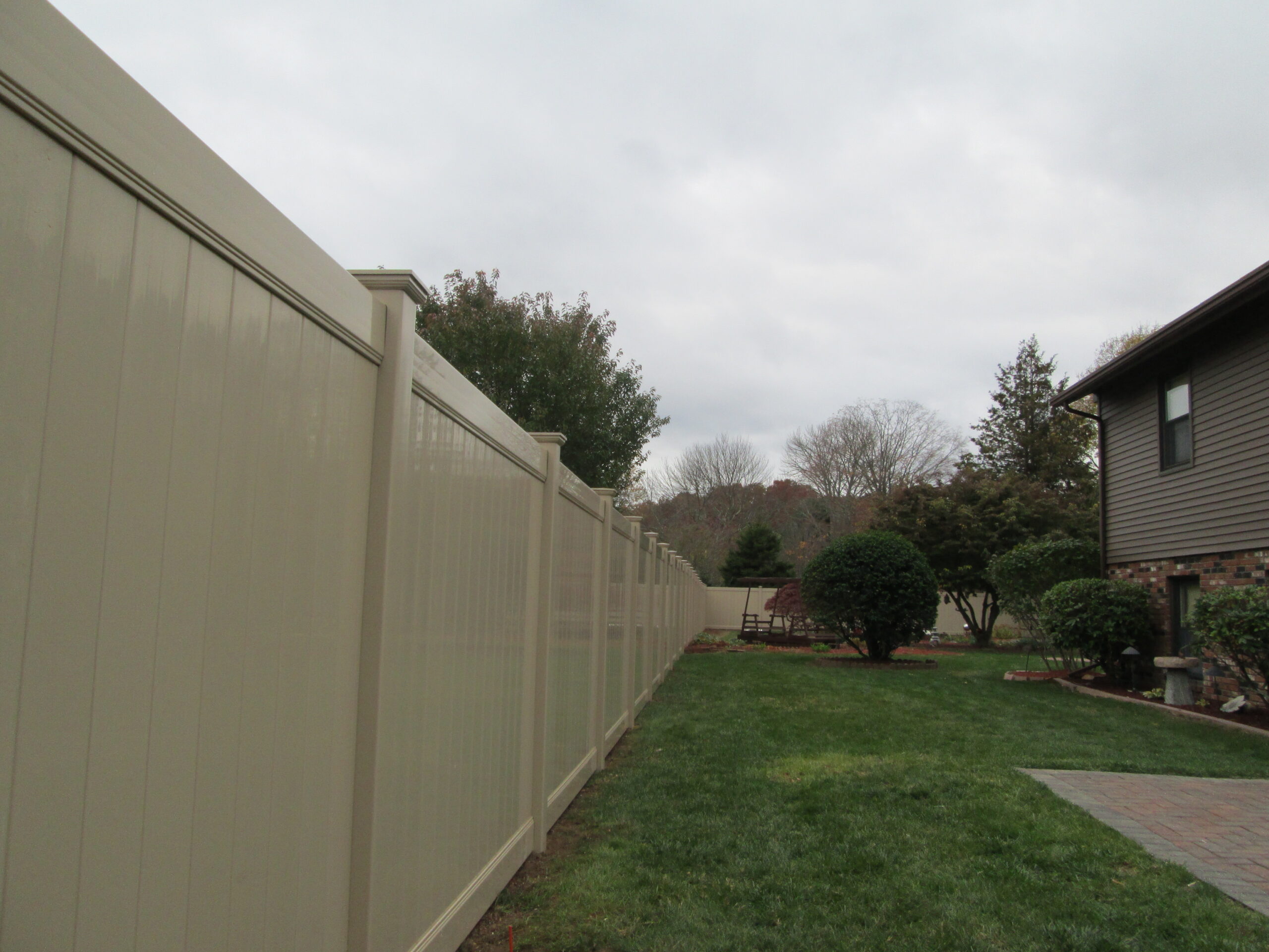 Tan vinyl privacy fence panels creating a secluded backyard in Connecticut