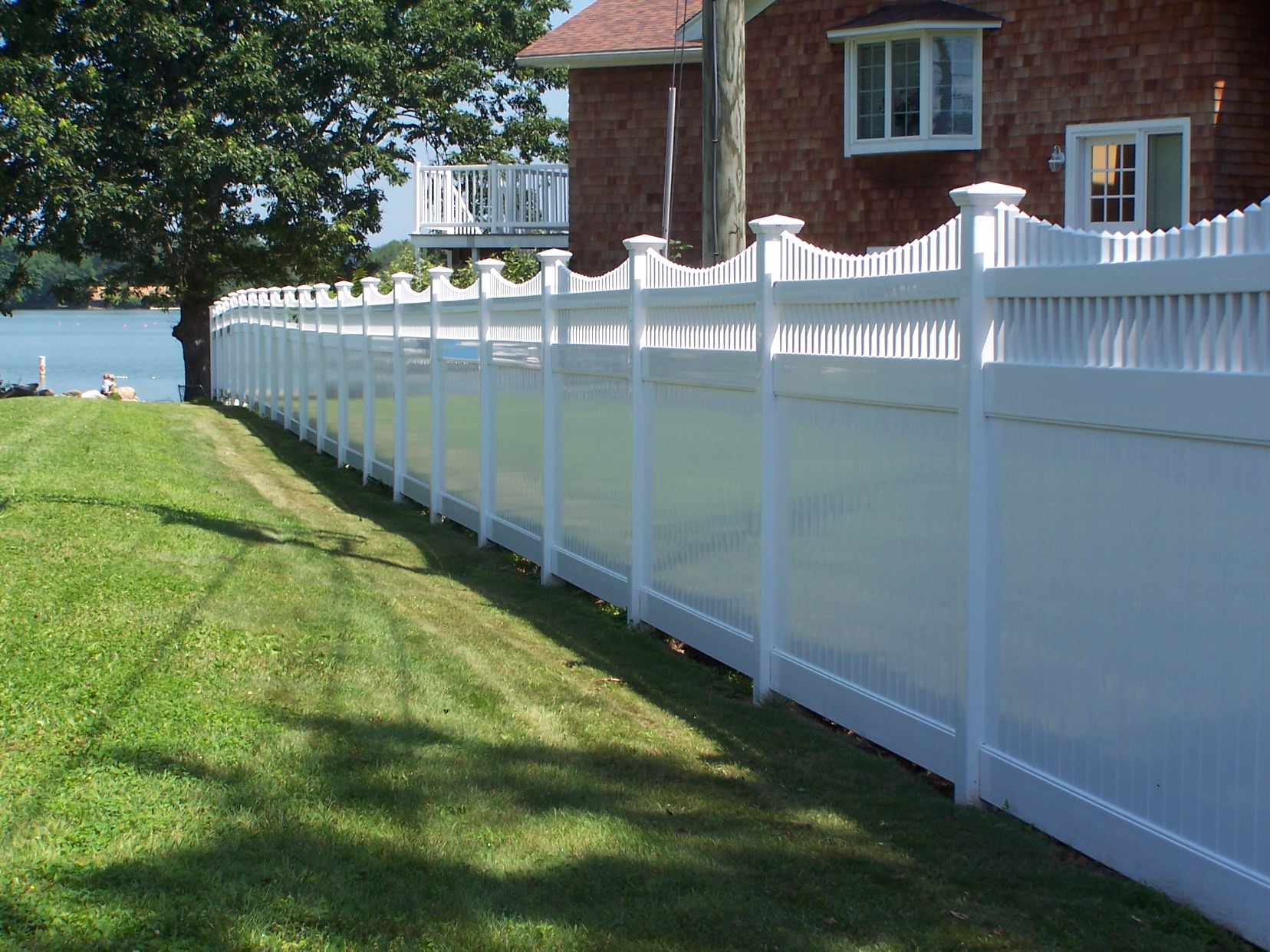 White vinyl picket fence along a lush green lawn in Connecticut
