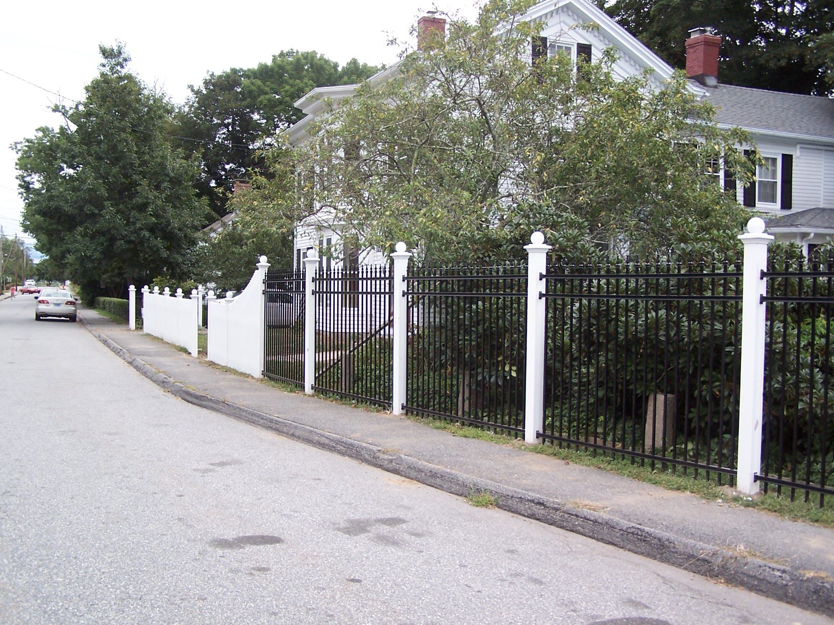 Tall black aluminum fence with decorative white stone pillars installed streetside in Connecticut by Arrow Fence