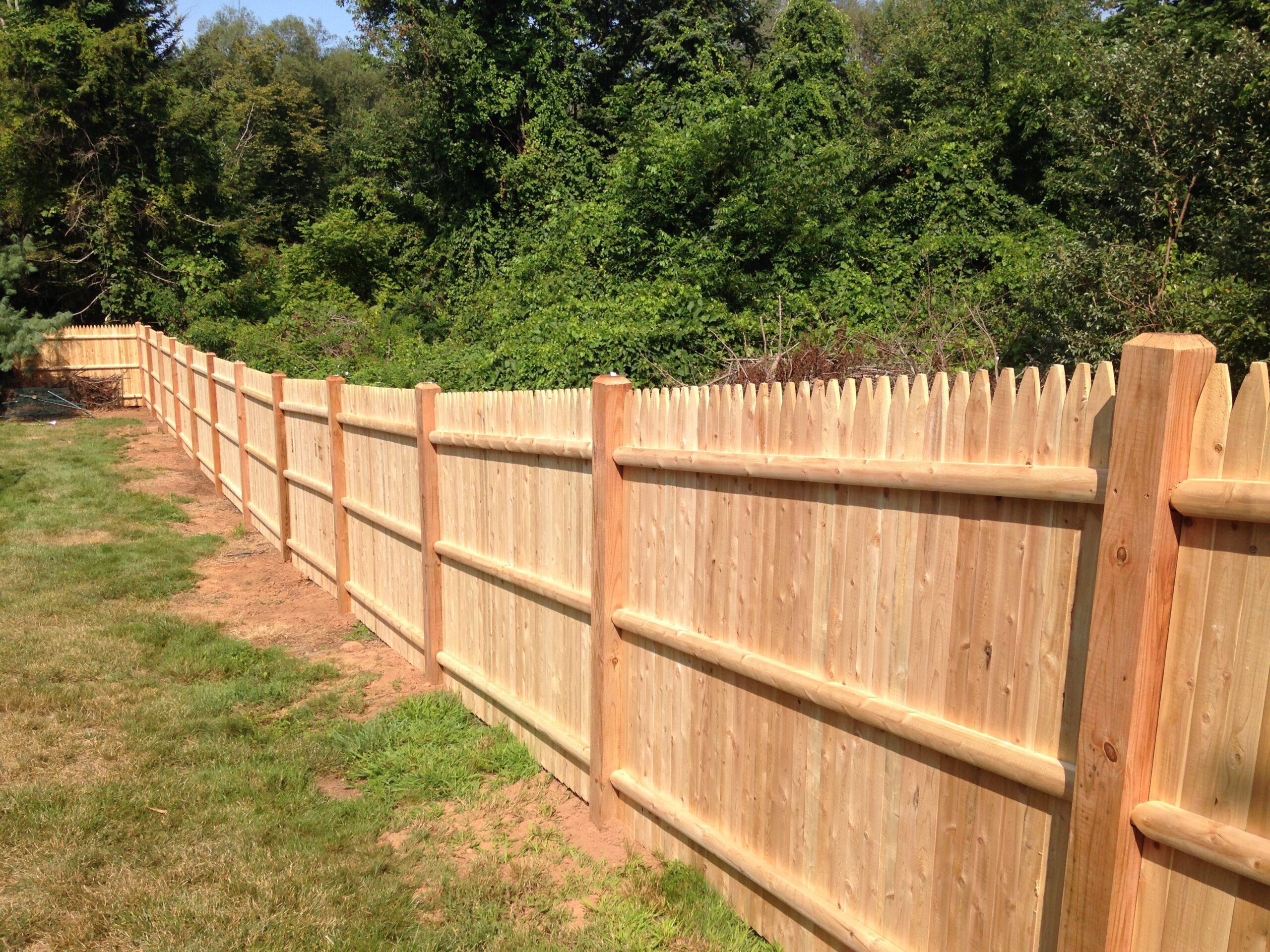 Cedar stockade privacy fence on sloped terrain showcasing Arrow Fence craftsmanship
