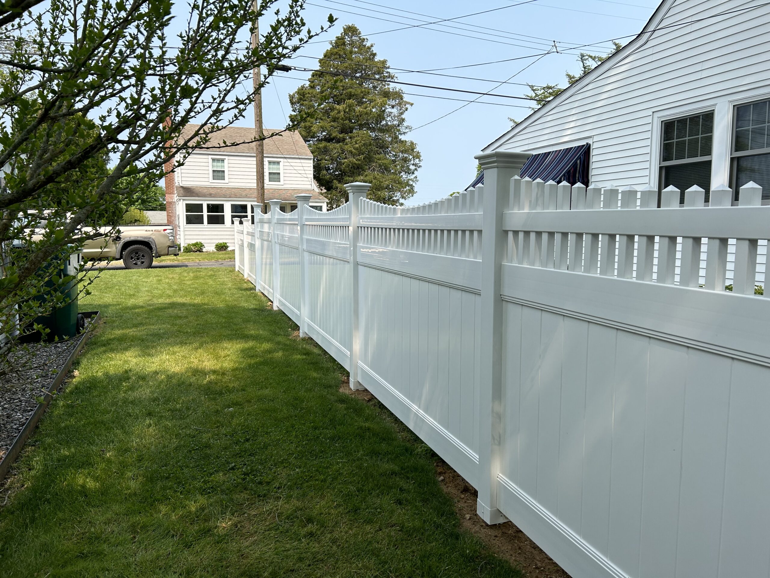 Long run of white vinyl picket fencing along a Connecticut residential yard