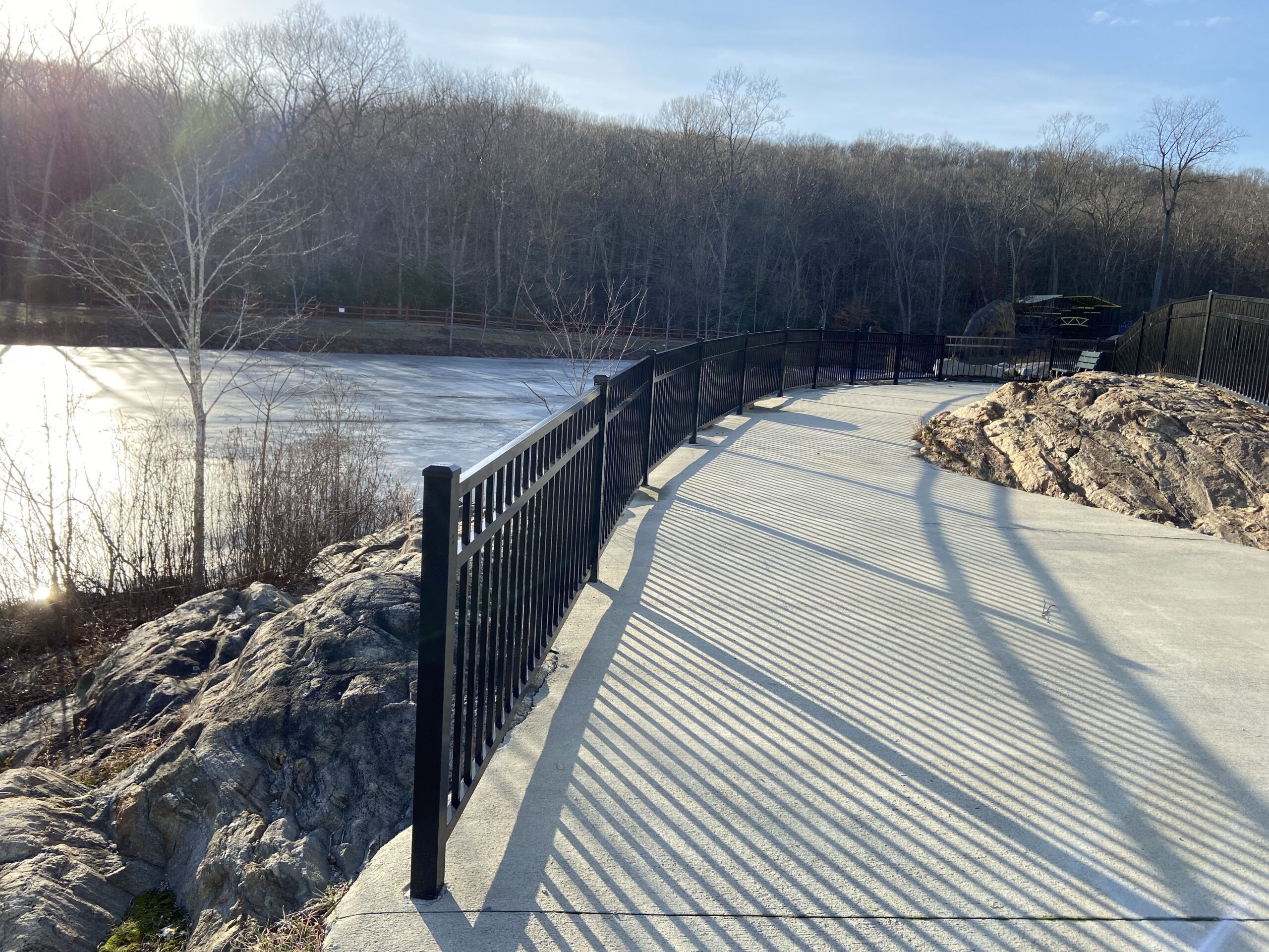 Aluminum safety railing along a curved public lakeside walkway installed by Arrow Fence in Connecticut