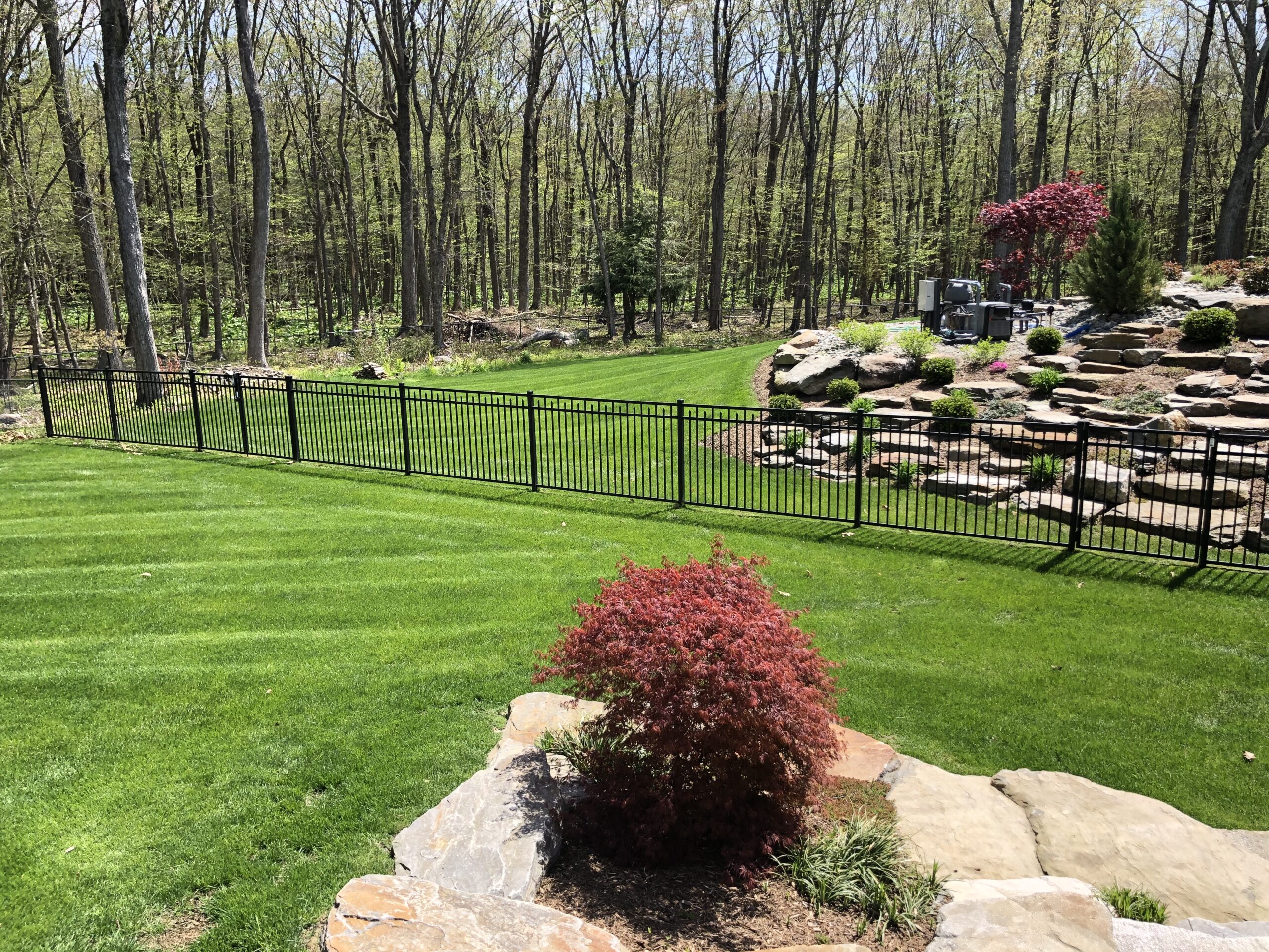 Wide shot of aluminum fencing installed along a rocky hillside in Connecticut by Arrow Fence