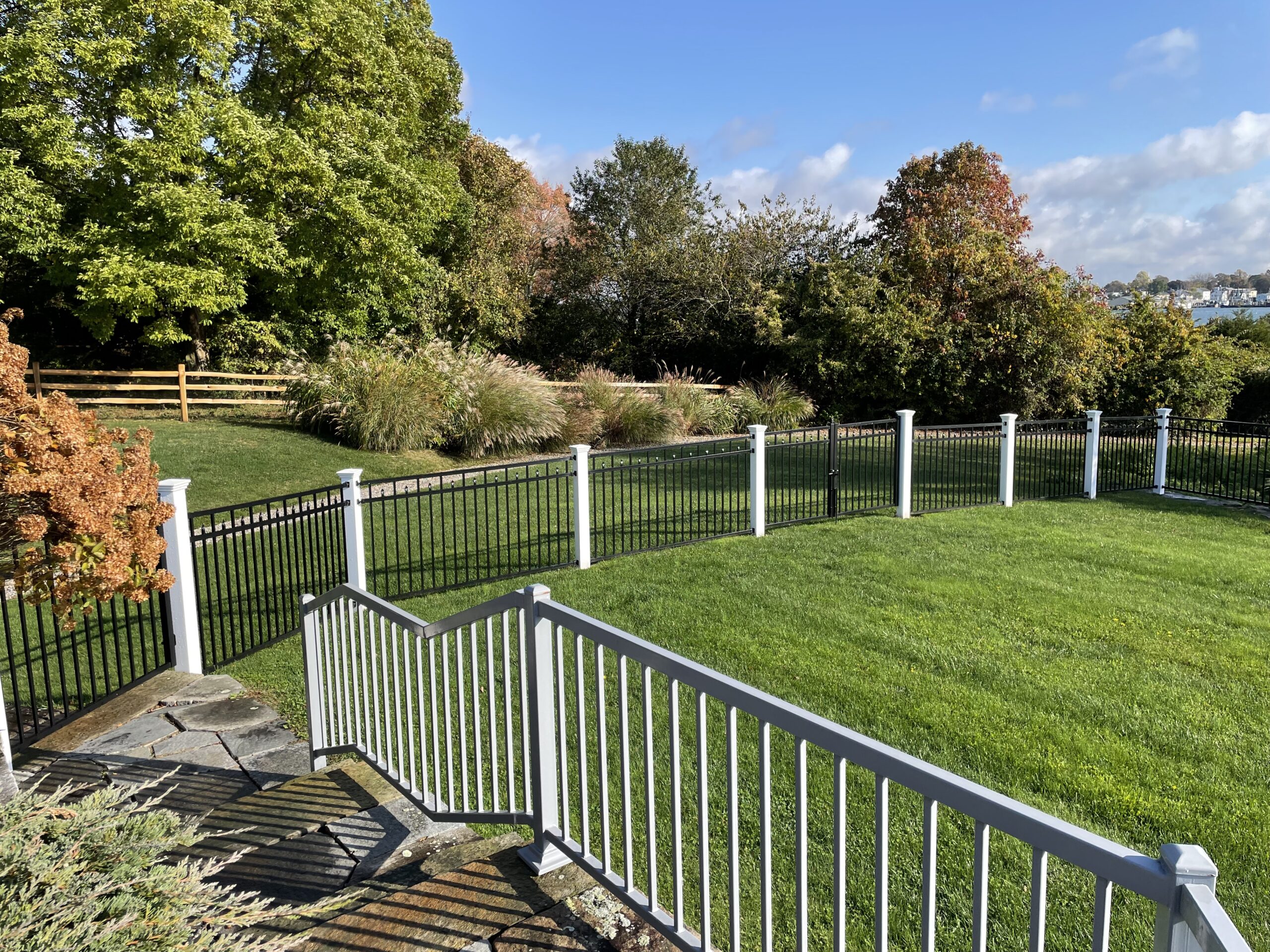 Black aluminum fence with white masonry pillar accents defining a Connecticut backyard