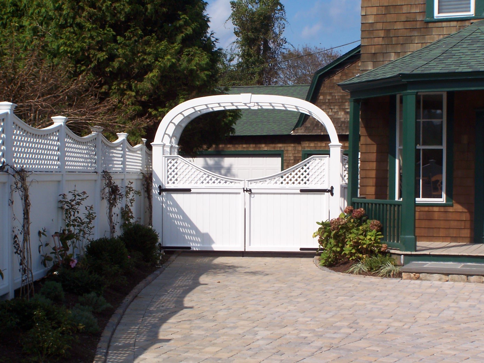 Custom cedar arbor with double gate and lattice-topped privacy fencing by Arrow Fence