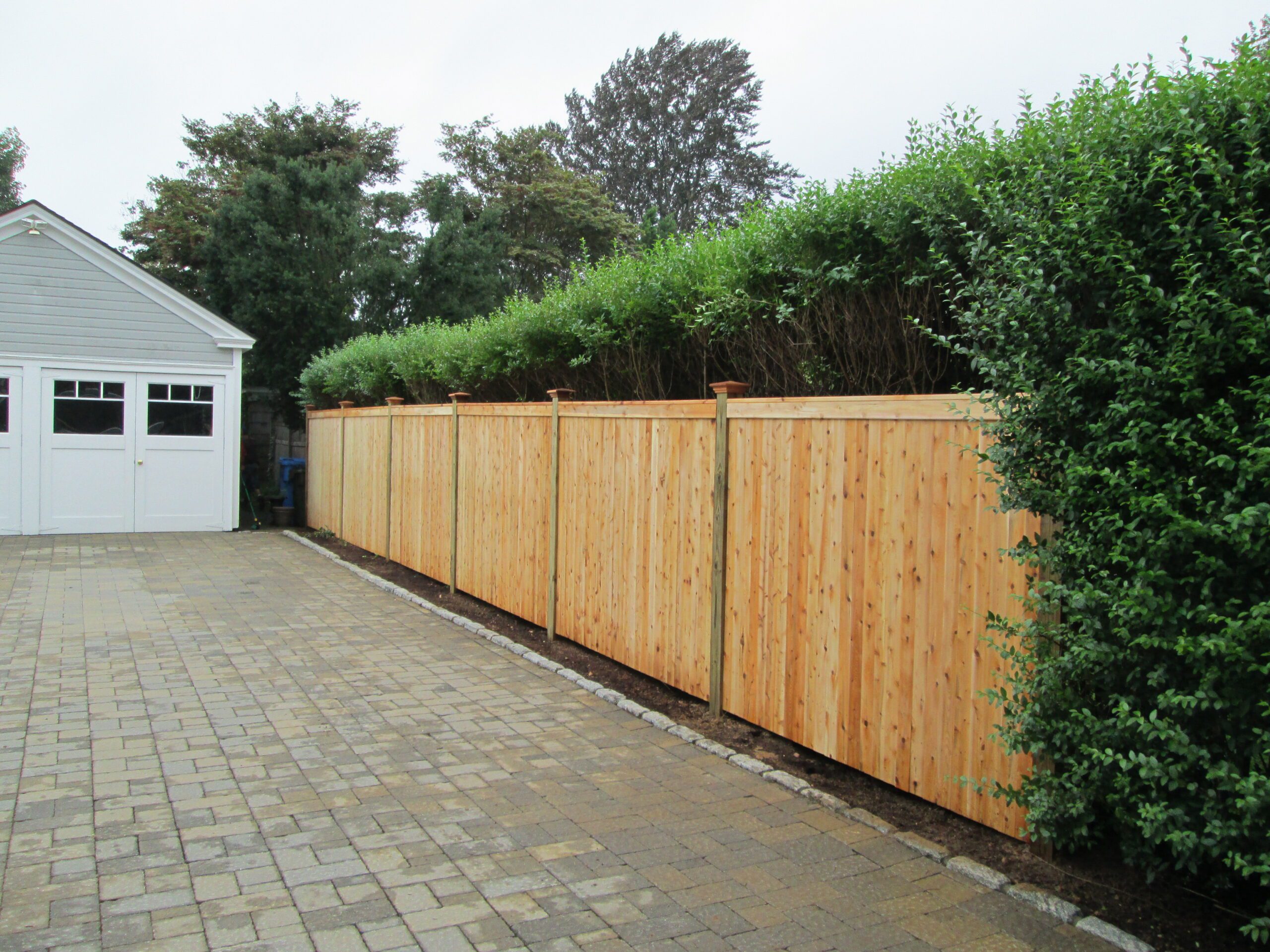 Cedar privacy fence separating a driveway from neighboring property in Connecticut