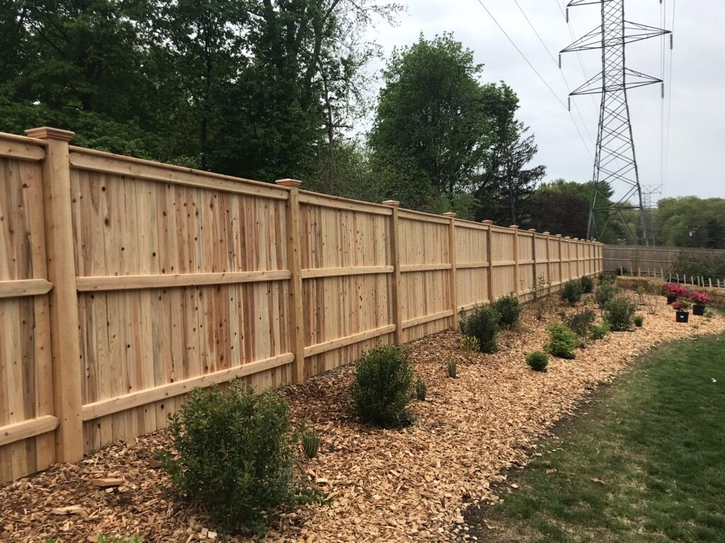 Custom cedar privacy fence installation with natural mulch border by Arrow Fence Inc. in Connecticut