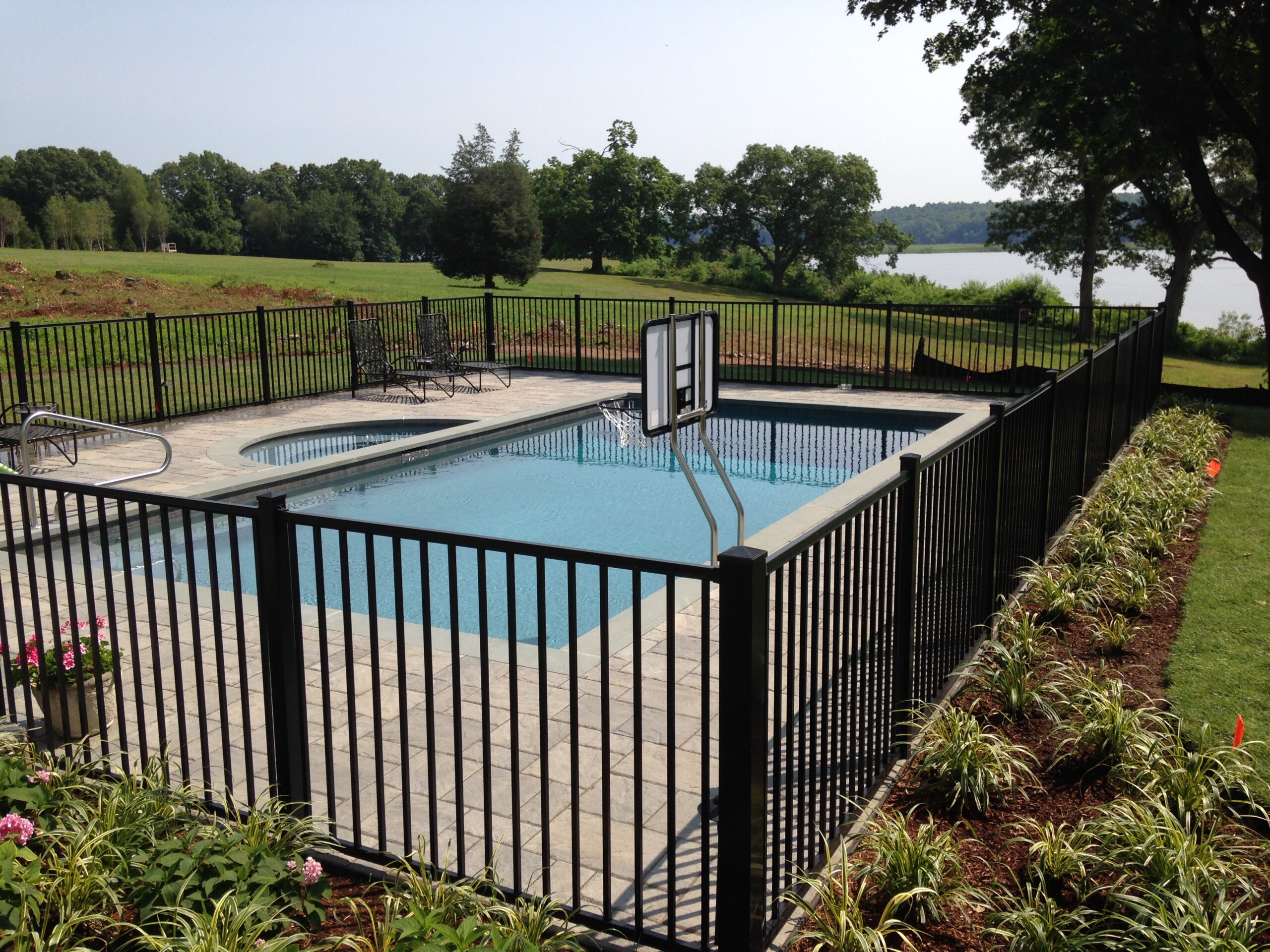 Depth of field view of aluminum fence extending through a landscaped Connecticut backyard