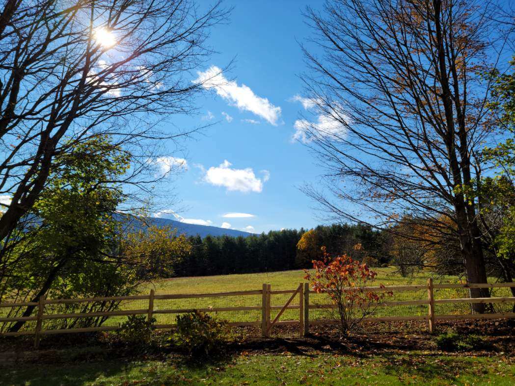 Post and rail gate opening to a scenic mountain meadow in Connecticut